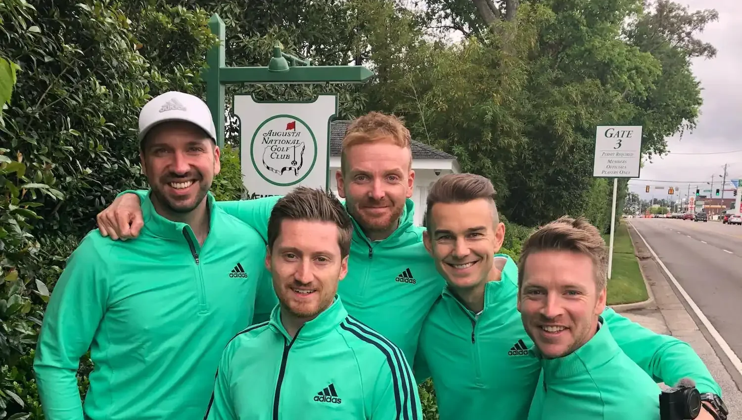 Piers Ward and Andy Proudman, along with two others, in green shirts posing for a picture at Augusta National Golf Course during the 2018 Masters.
