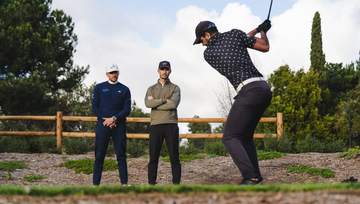 PGA coaches Piers and Andy watch Aaron Rai hit driver during golf lesson.